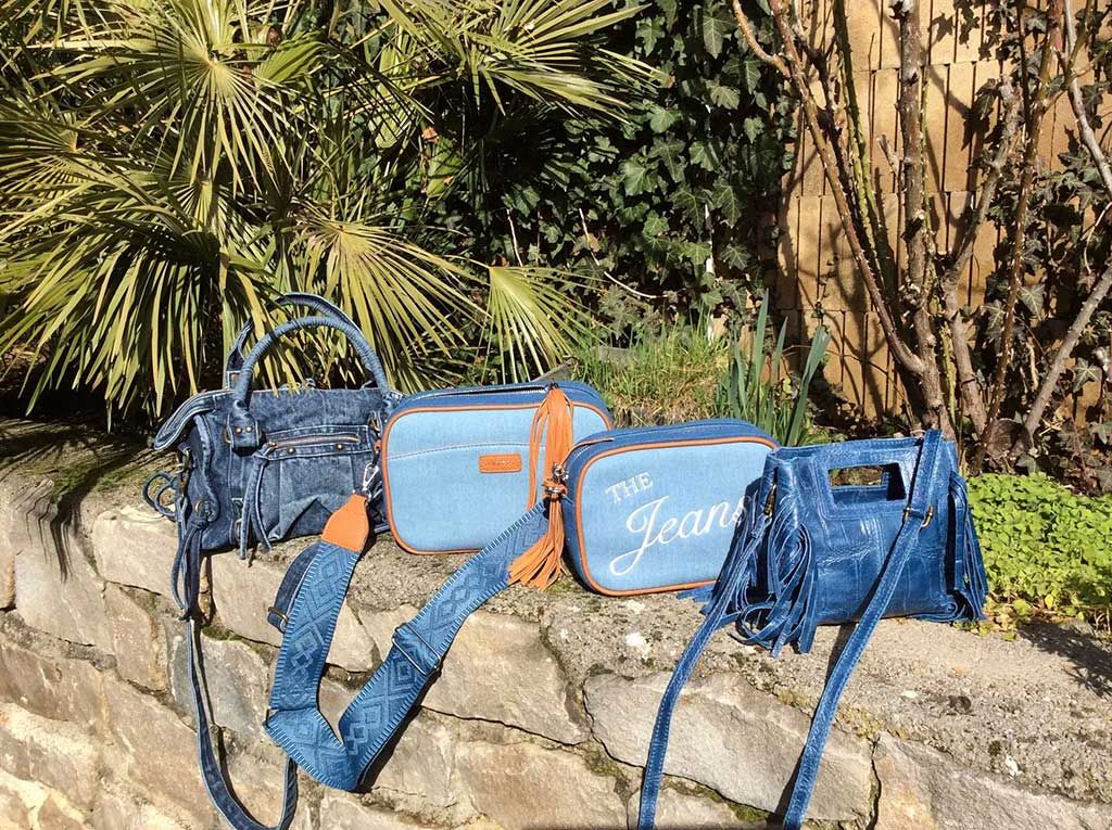Des sacs de sport bleus et oranges sur un muret en pierre dans un jardin, avec des feuilles de palmier en arrière-plan.