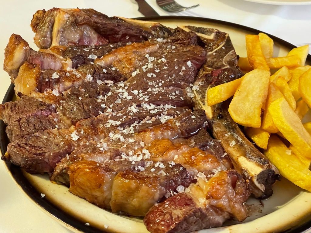 Gran filete a la parrilla con sal marina, servido con una guarnición de patatas fritas gruesas.