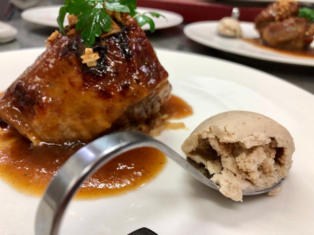 Primer plano de un plato emplatado que contiene carne glaseada y salsa.