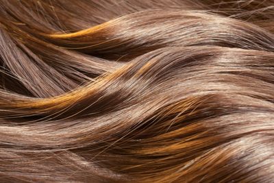 Eine Hand hält Alufolie in der Nähe der gesträhnten Haare.