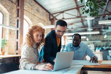 Chef d'entreprise avec ses collaborateurs devant un ordinateur portable