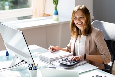 Comptable devant son ordinateur avec un classeur et une calculette