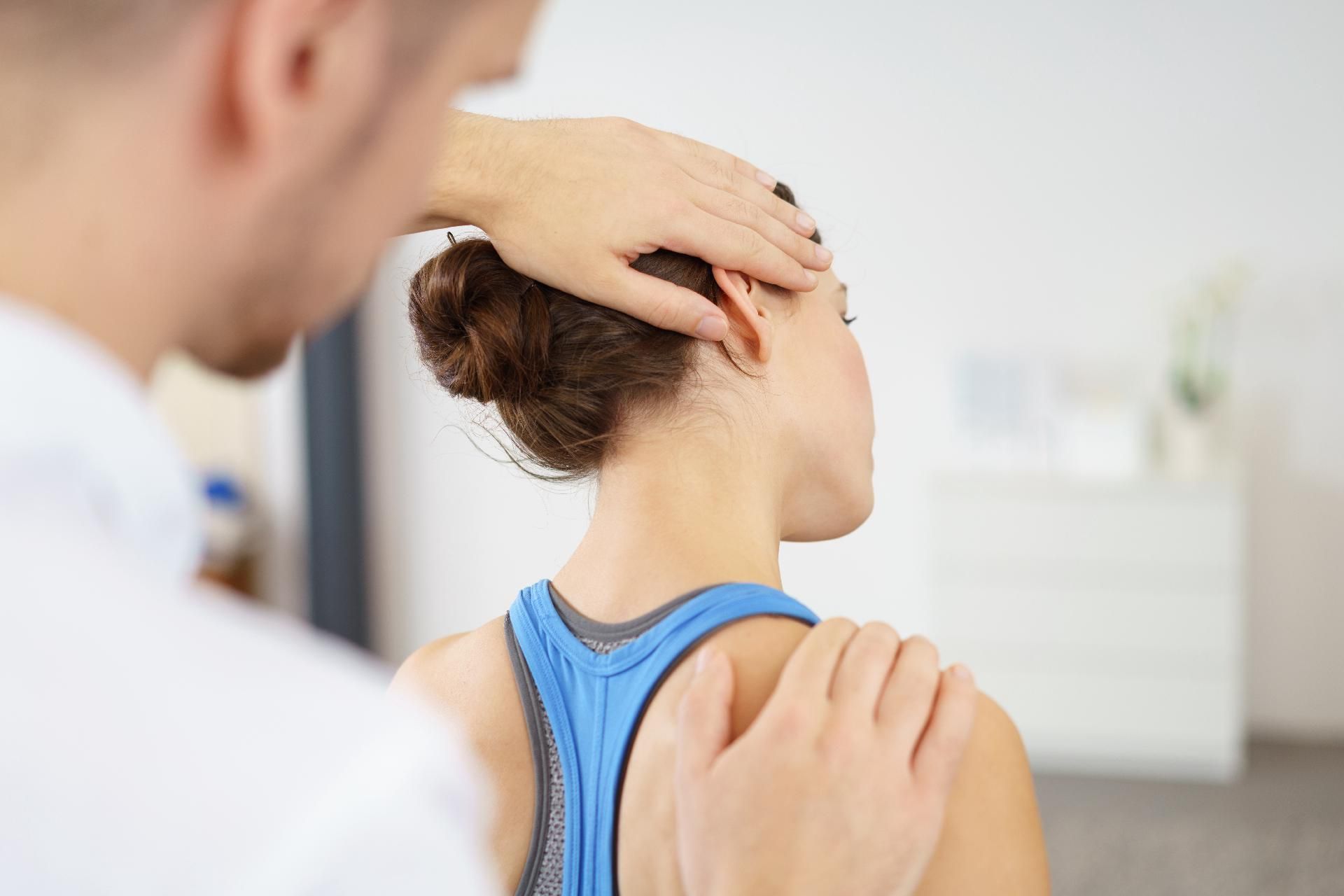 Physiotherapeut untersucht Nacken und Schulter einer Frau in einer Klinik