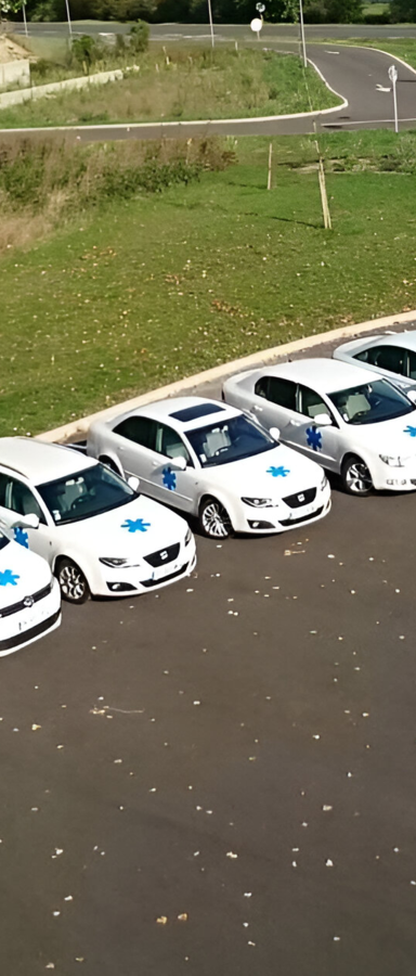 Voitures blanches à étoiles bleues garées sur l'asphalte. Herbe verte et route en arrière-plan.