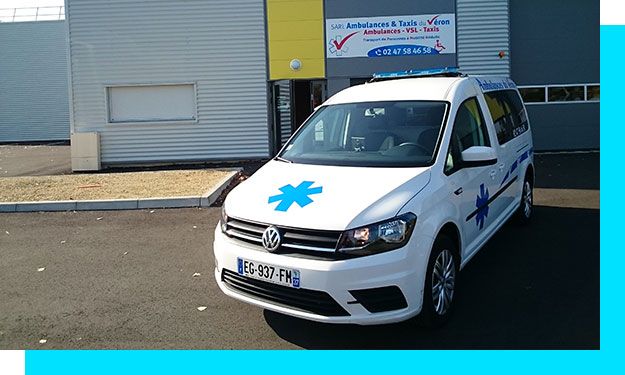 Ambulance blanche garée devant un bâtiment portant un panneau médical.