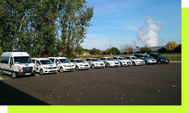 Une rangée de véhicules de police blancs et bleu clair stationnés sur l'asphalte.