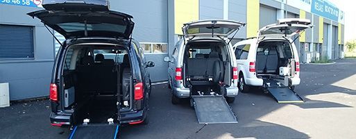 Trois fourgonnettes accessibles sont stationnées avec les rampes déployées.
