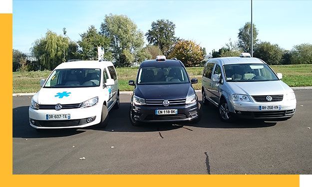 Trois fourgonnettes de taxi étaient garées dehors par une journée ensoleillée.