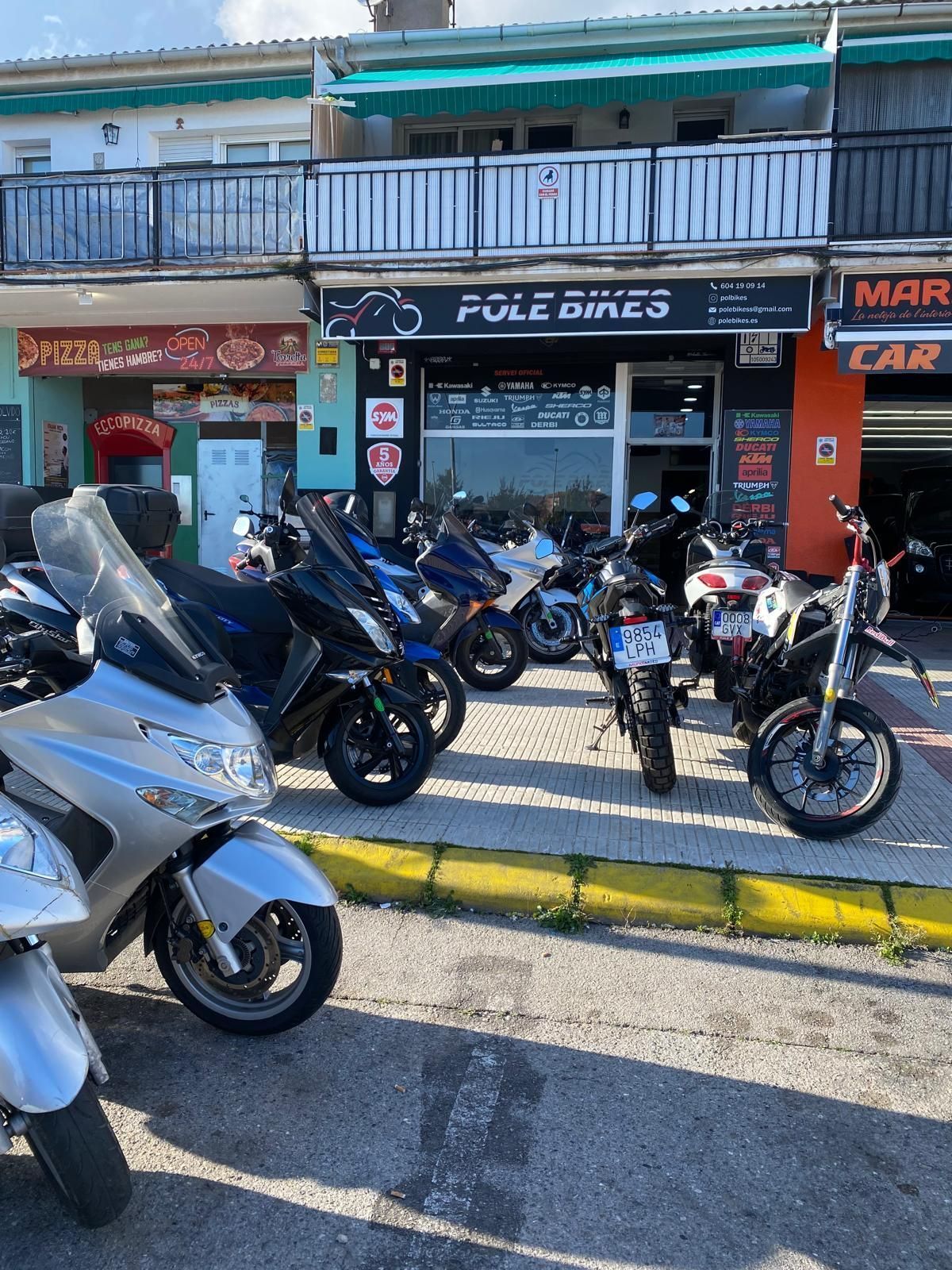 Hay muchas motocicletas estacionadas frente a una tienda.