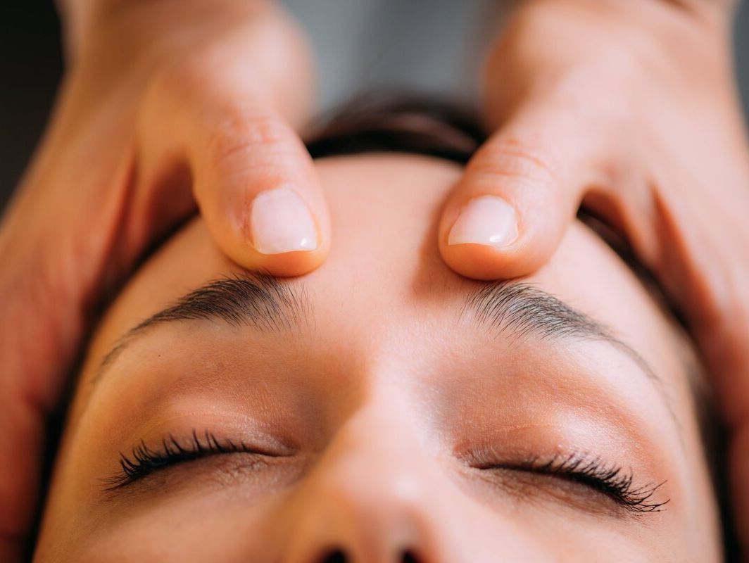 Una mujer está recibiendo un masaje en la cabeza con los ojos cerrados.