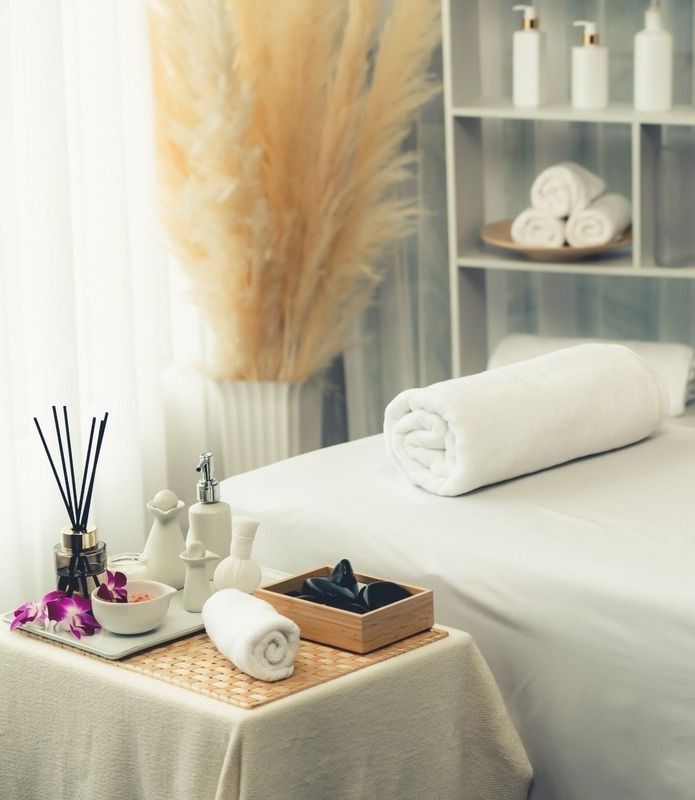 Una mesa con toallas y flores en una sala de spa.