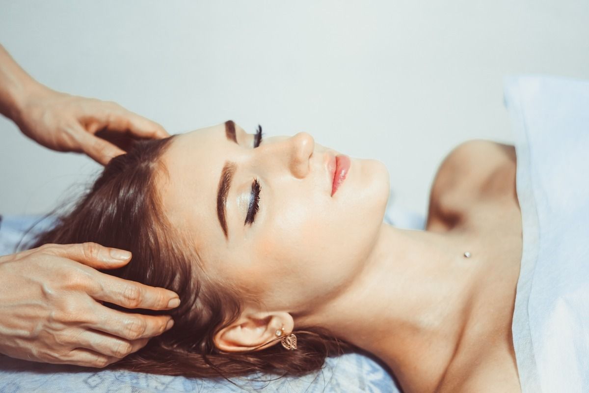 Una mujer está recibiendo un masaje de cabeza en un spa.