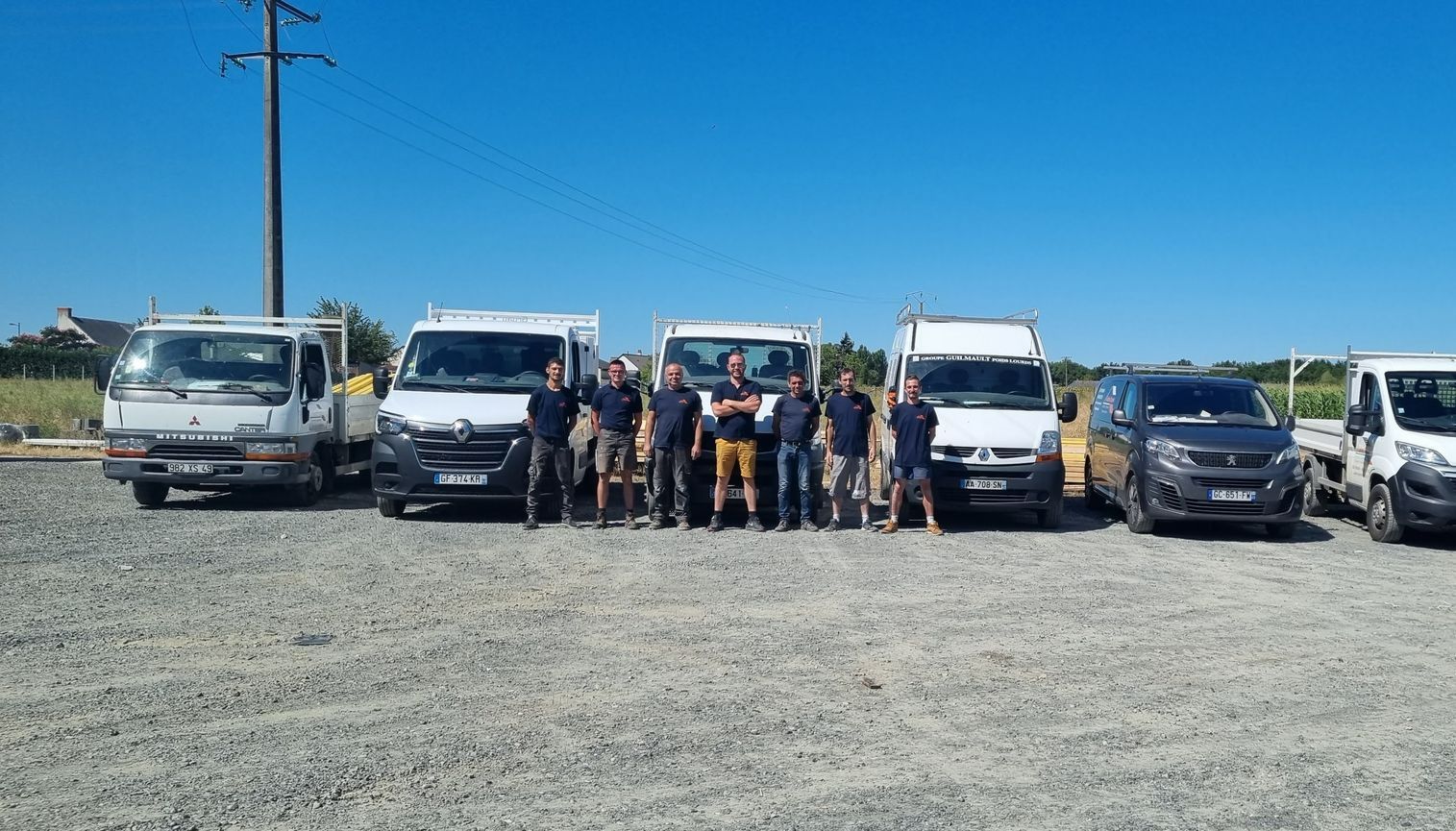 Un groupe d'hommes posant devant des camionnettes.