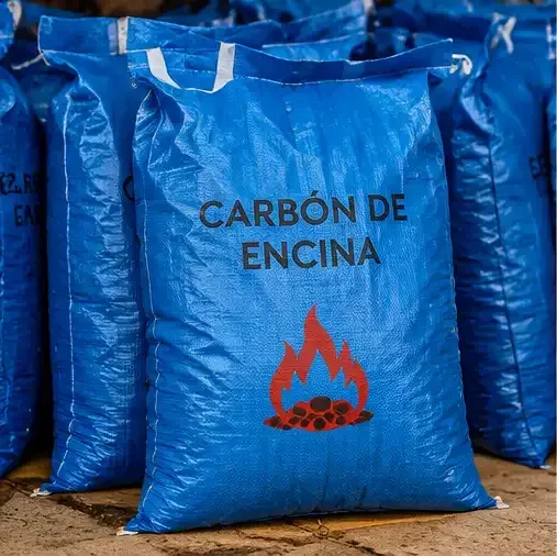 Bolsas azules de carbón etiquetadas como «CARBÓN DE ENCINA», con un icono de una llama roja, apiladas en un almacén.
