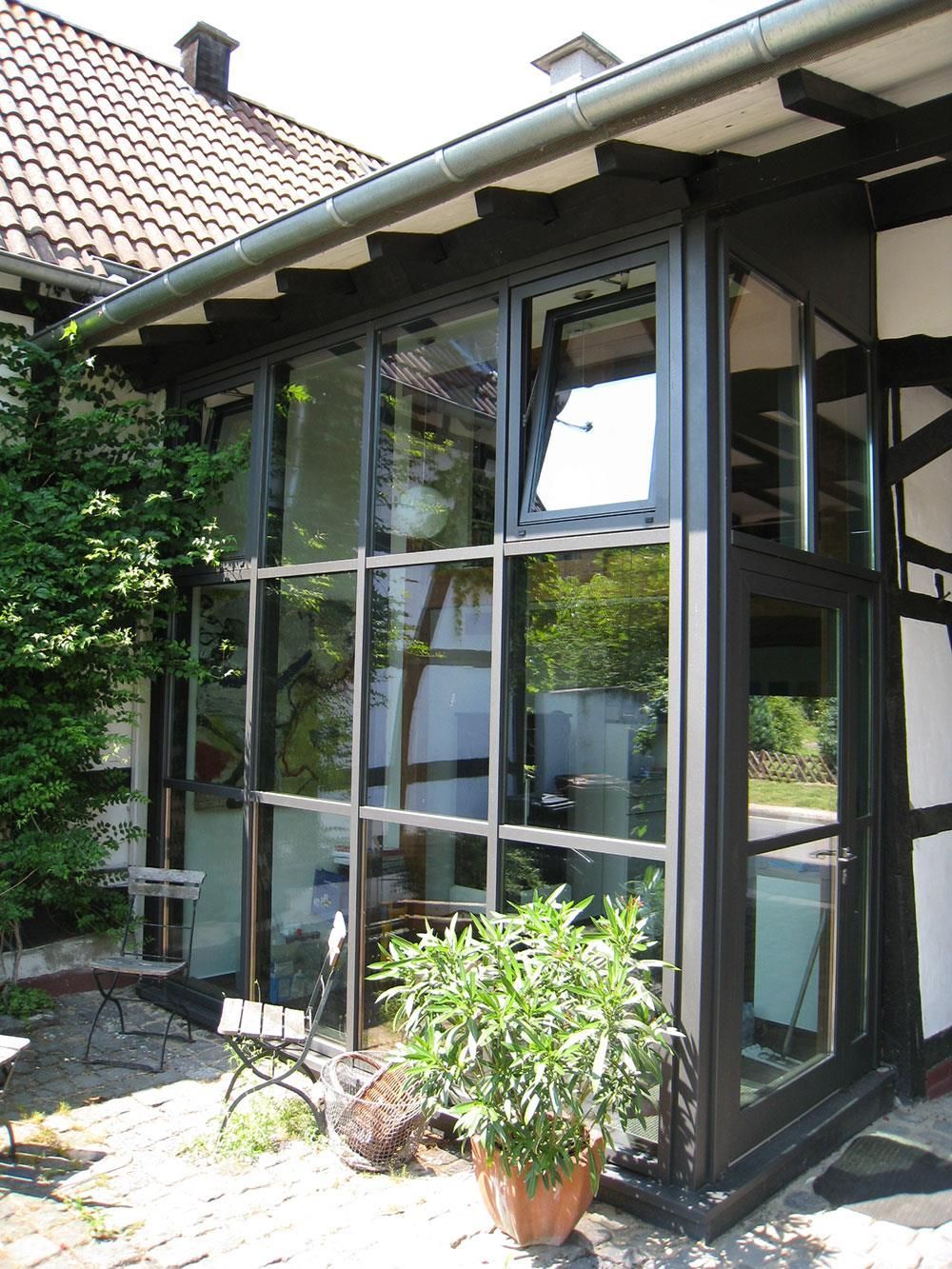 Ein Haus mit vielen Fenstern und einer Topfpflanze davor