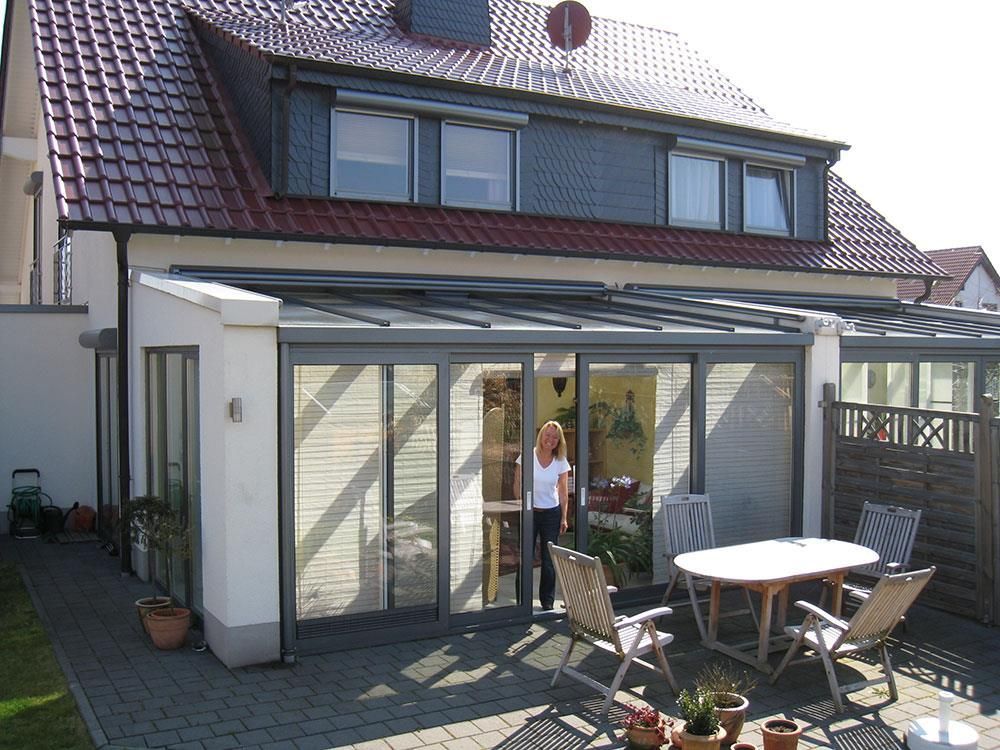 Eine Frau steht vor einem Haus mit einem Tisch und Stühlen