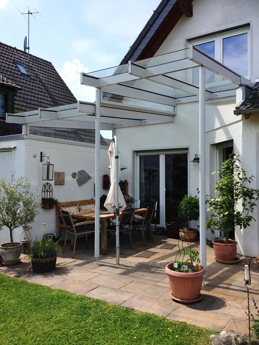 Ein weißes Haus mit einer Pergola und Topfpflanzen davor