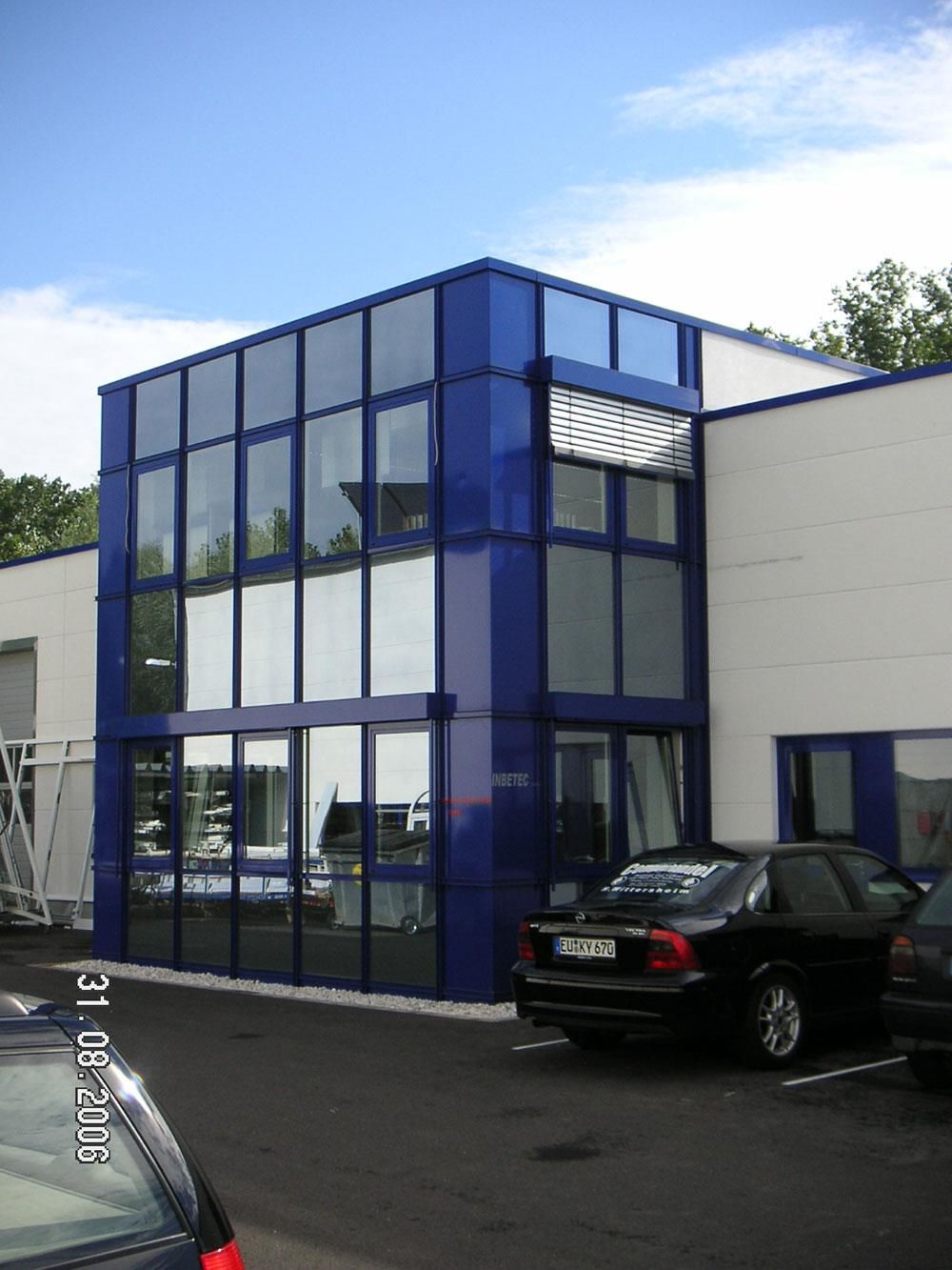 Ein blau-weißes Gebäude mit einem davor geparkten Auto