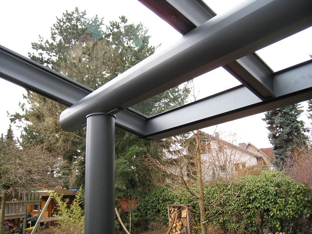 Eine Metallkonstruktion mit Glasdach und Bäumen im Hintergrund