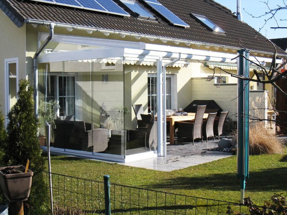 Ein Haus mit einer überdachten Terrasse mit Tisch und Stühlen