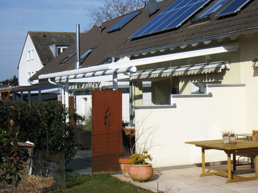 Ein Haus mit Pergola und Sonnenkollektoren auf dem Dach