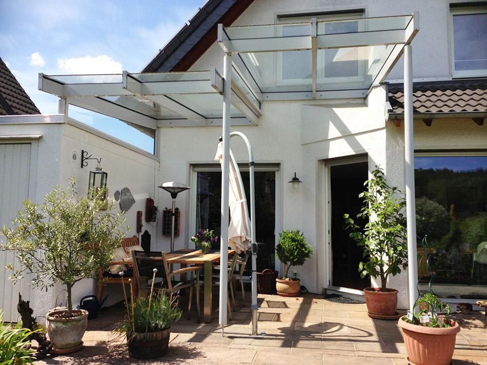 Eine Terrasse mit Tisch und Stühlen unter einem Glasdach