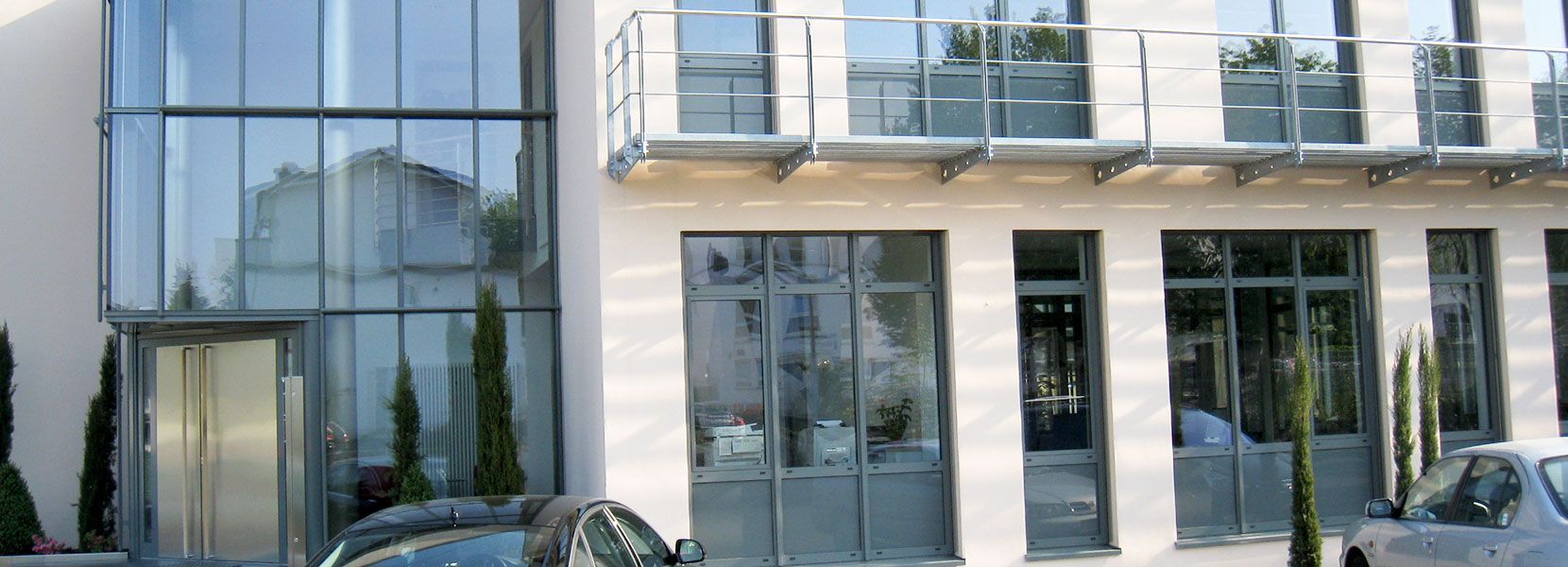 Ein Auto ist vor einem Gebäude mit vielen Fenstern geparkt