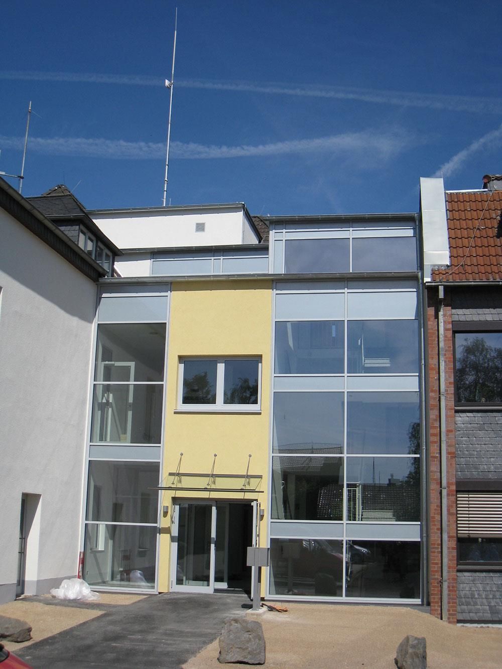 Ein gelbes Gebäude mit vielen Fenstern steht neben einem Backsteingebäude