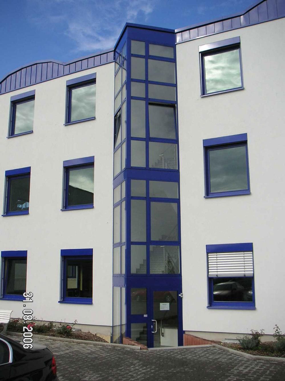 Ein weißes Gebäude mit blauen Fenstern und einem davor geparkten LKW