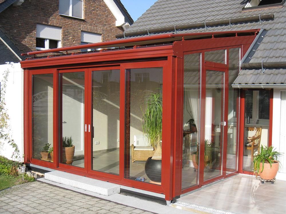 Ein Haus mit einem roten Wintergarten mit vielen Fenstern