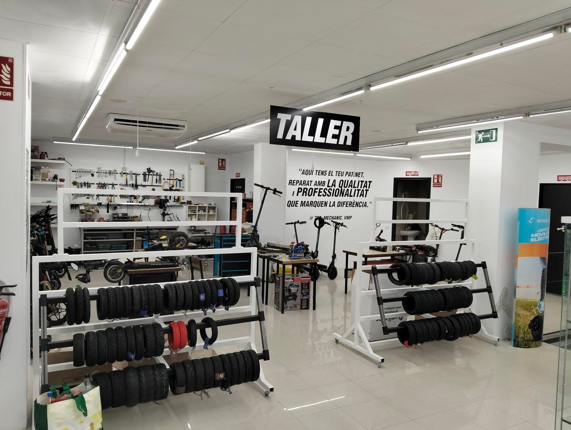 Una fila de patinetes eléctricos están aparcados delante de un mostrador en un edificio más alto.