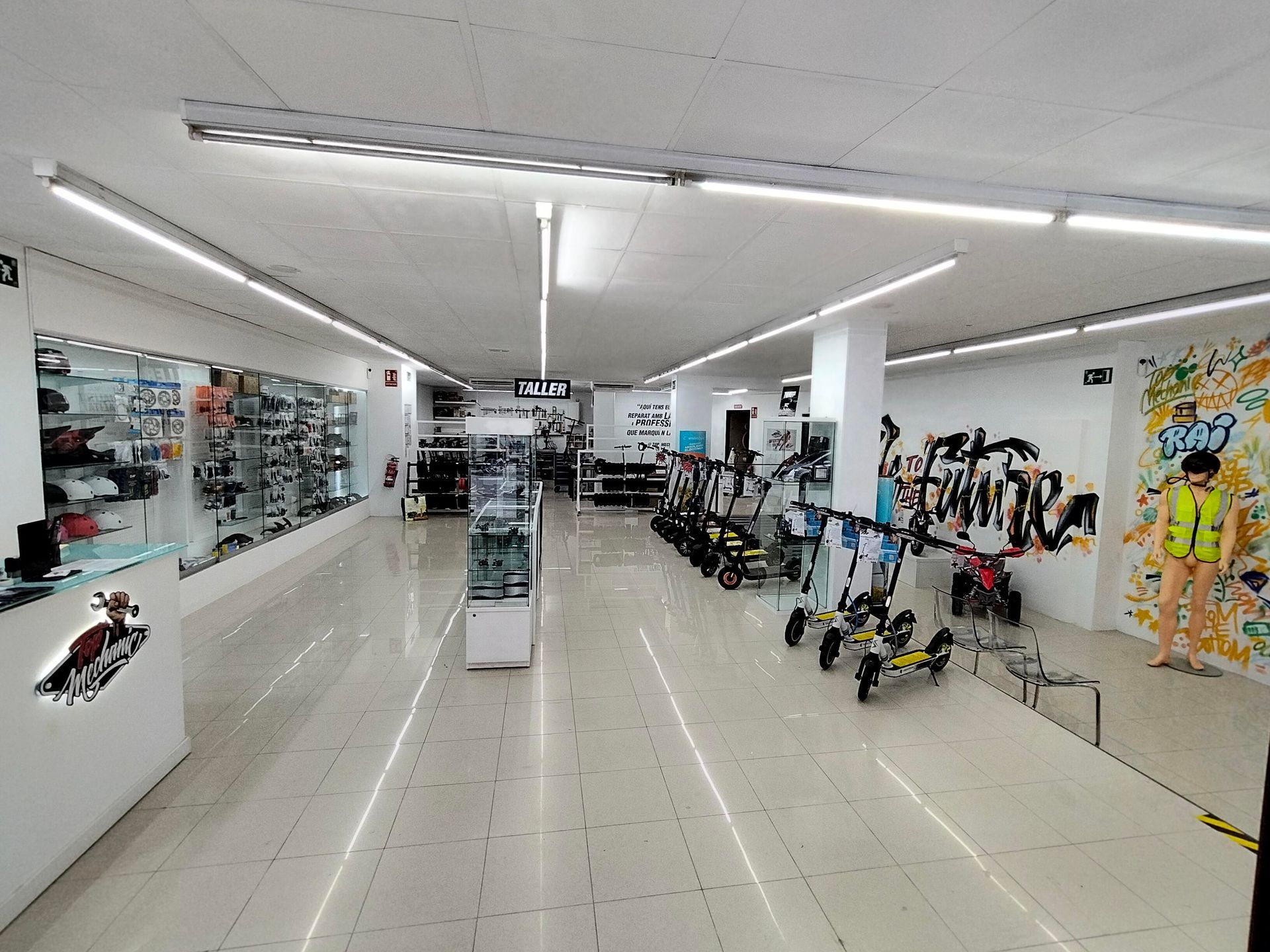 Una fila de patinetes eléctricos están aparcados delante de un mostrador en un edificio más alto.