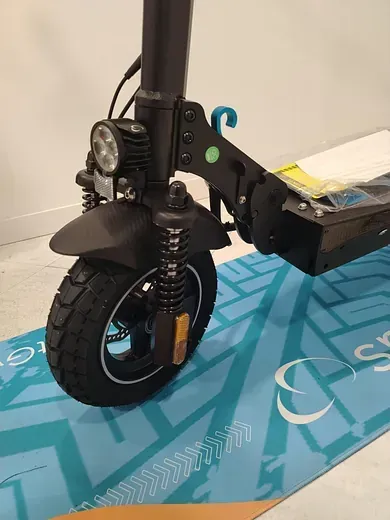 Un scooter eléctrico negro está sentado sobre una alfombra azul.