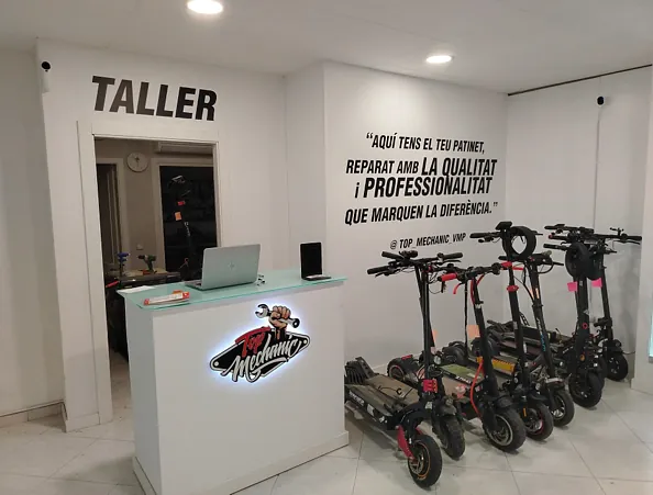 Una fila de patinetes eléctricos están aparcados delante de un mostrador en un edificio más alto.