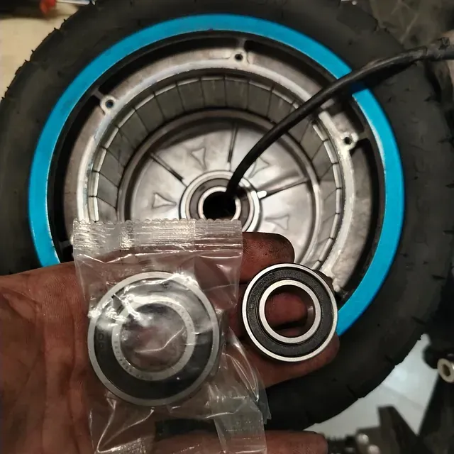 Una persona sostiene una bolsa de rodamientos delante de una rueda.