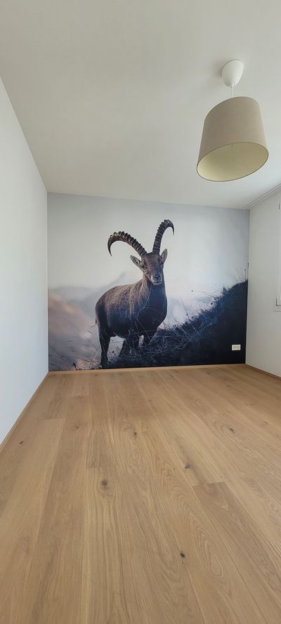 Eine teilweise fertiggestellte Holzveranda mit grün gestrichenen Balken und Zierkonsolen unter einer weissen Decke.