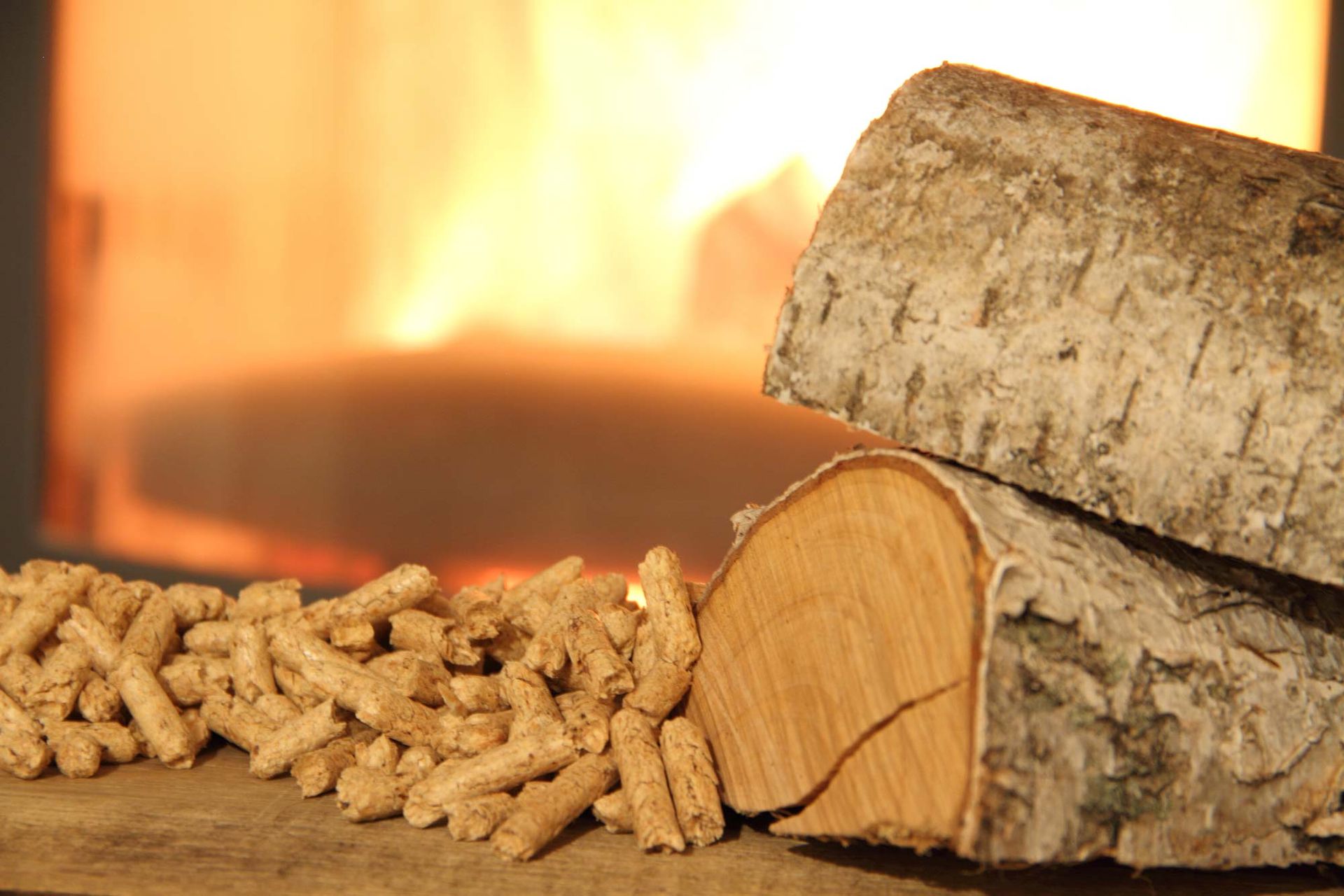 Ein Stapel Holzscheite und Holzpellets vor einem Kamin.