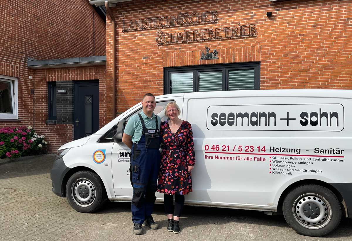 Eine Gruppe von Menschen steht vor zwei Lieferwagen.