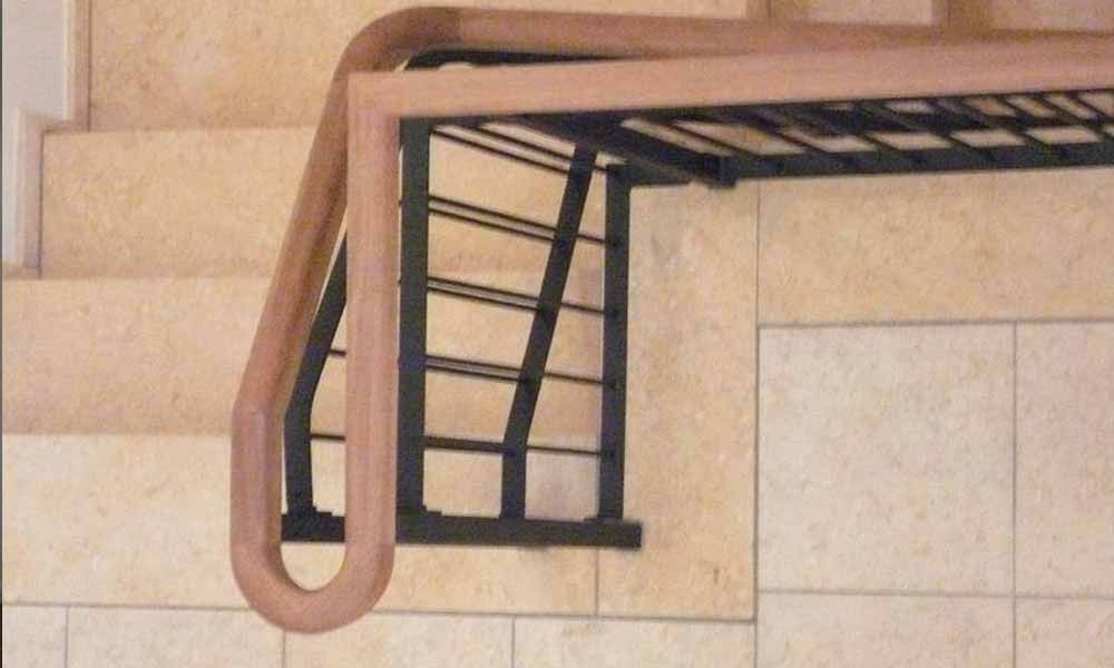 eine Nahaufnahme einer Treppe mit Holzhandlauf und Metallgeländer .