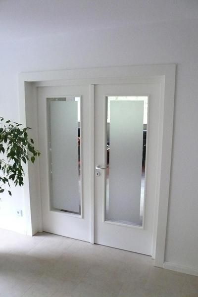 eine weiße Tür mit einem frostigen Glasfenster in einem Raum .