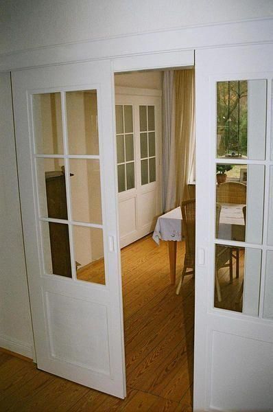 eine weiße Schiebetür führt in ein Esszimmer mit einem Tisch und Stühlen .