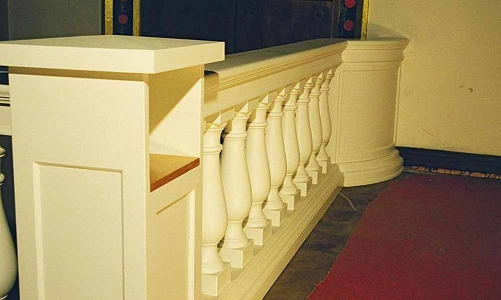 ein weißer Geländer in einem Raum neben einem roten Teppich .