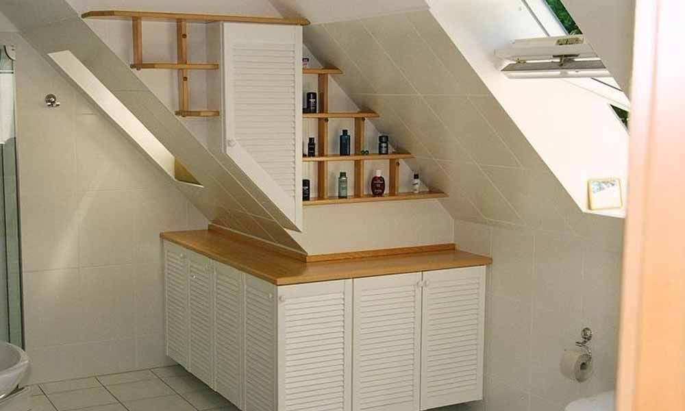 ein Badezimmer mit weißen Schränken und Regalen im Dachboden