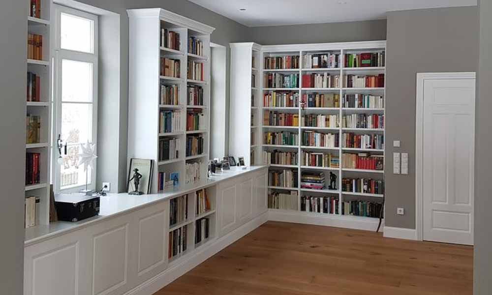 ein Wohnzimmer mit weißen Bücherregalen und einem Holzboden .