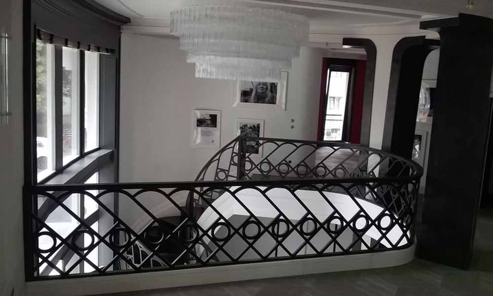 eine Treppe mit einem schwarzen Metallgeländer und einem Kronleuchter im Hintergrund