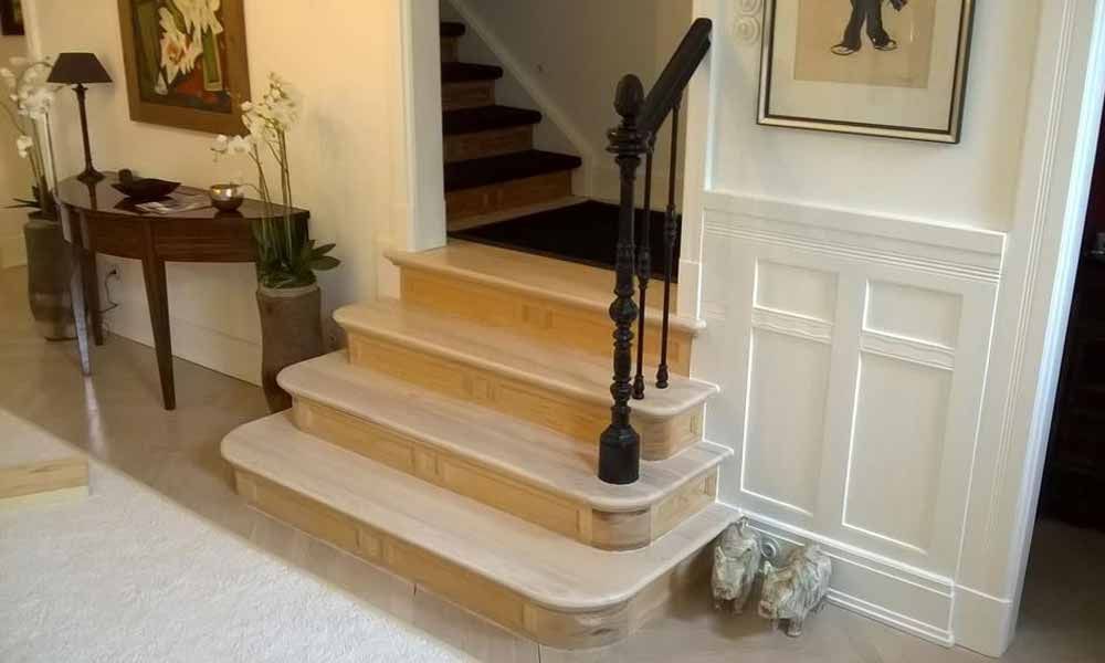 eine Holztreppe mit einem schwarzen Handlauf in einem Haus .