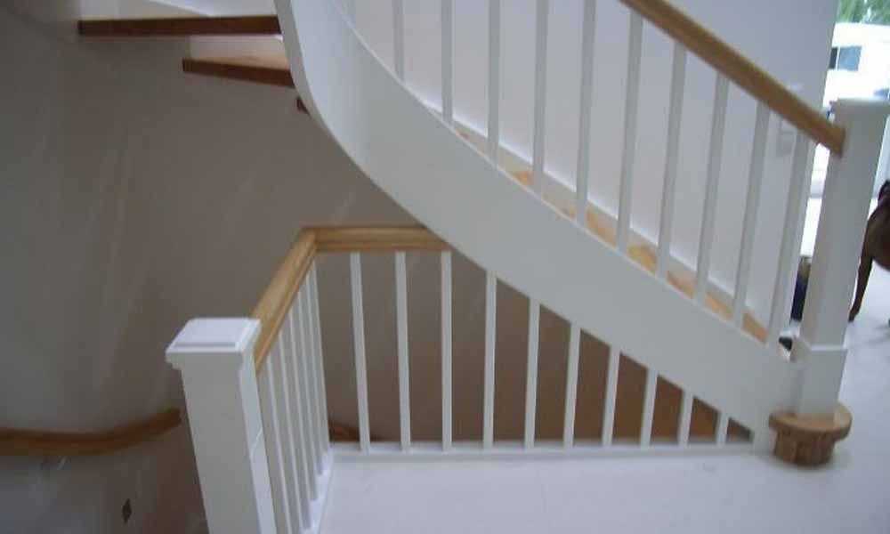 eine weiße Treppe mit Holzhandlauf und Handlauf in einem Haus .