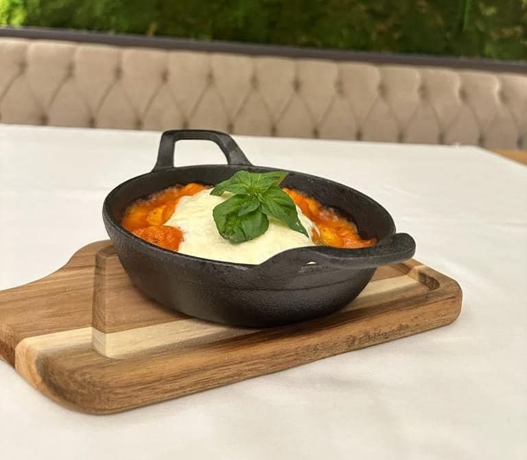 Un plato de comida está sobre una tabla de cortar de madera sobre una mesa.