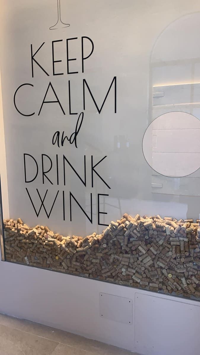 Un cartel en una pared que dice mantén la calma y bebe vino.