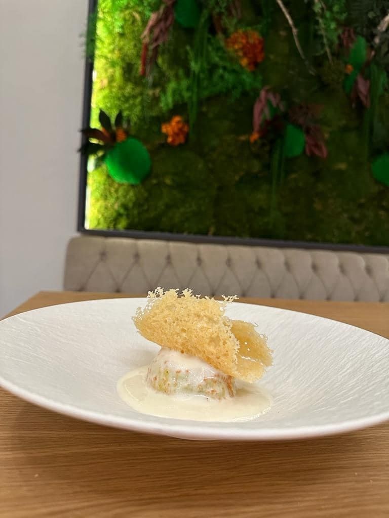 Un plato blanco con un trozo de comida encima está sobre una mesa de madera.